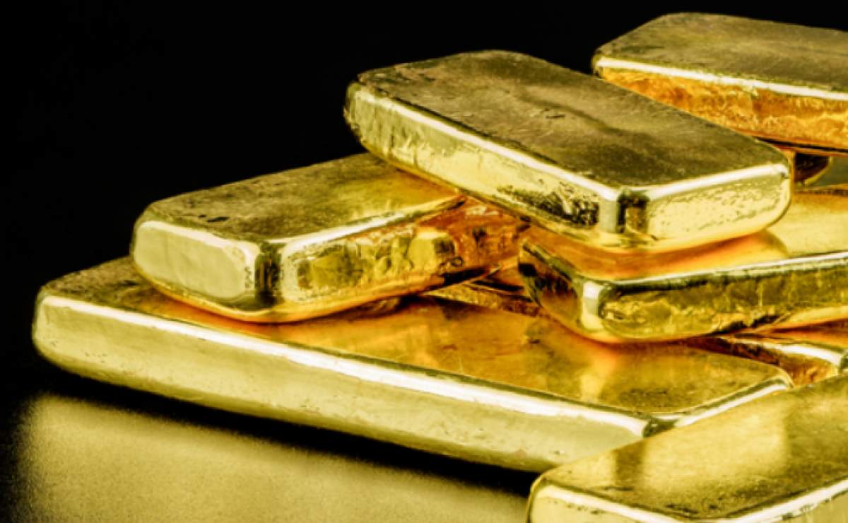 Stacked gold bullion bars on a dark reflective surface