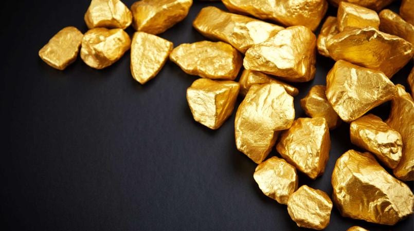 Gold nuggets scattered across a dark background