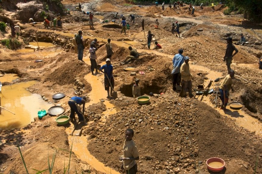 Artisanal miners working pits and sluices across an open gold mining site